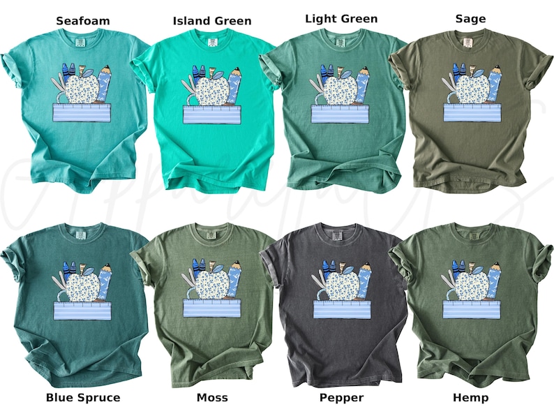May include: A set of ten t-shirts featuring a graphic of a red apple with school supplies, including pencils, scissors, and a ruler. The shirts are available in ten different colors: Seafoam, Island Green, Light Green, Sage, Blue Spruce, Moss, Pepper, Hemp, and two more.
