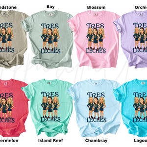May include: A collection of eight t-shirts in various colors, each featuring a graphic of three women and the text "TRES LECHES". Colors include beige, light green, pink, purple, red, teal, light blue, and turquoise.
