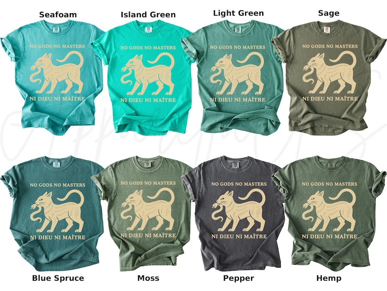 May include: A collection of eight t-shirts in various colors, including seafoam, island green, and sage. Each shirt features a graphic of a cat holding a snake, with the text "NO GODS NO MASTERS" and "NI DIEU NI MAITRE" printed on the front.