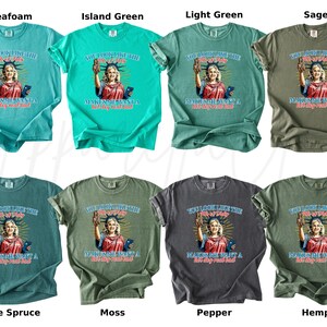 Puede incluir: Ocho camisetas en varios colores, incluyendo espuma de mar, verde isla, verde claro, salvia, abeto azul, musgo, pimienta y c&aacute;&ntilde;amo. Cada camiseta presenta un gr&aacute;fico de la Estatua de la Libertad con el texto: "You look like the 4th of July, makes me want a hot dog real bad."