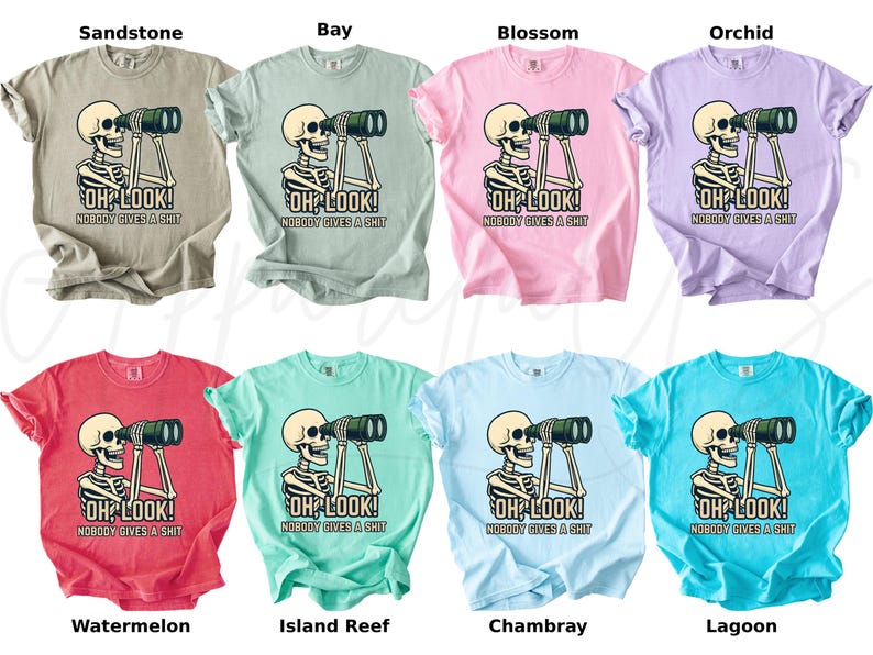 Op de afbeelding: Een collectie van acht t-shirts in verschillende kleuren, elk met een skelet dat door een verrekijker kijkt. De tekst "OH LOOK! NOBODY GIVES A SHIT" staat eronder. Kleuren zijn beige, lichtblauw, roze, paars, rood, teal, lichtblauw en turquoise.