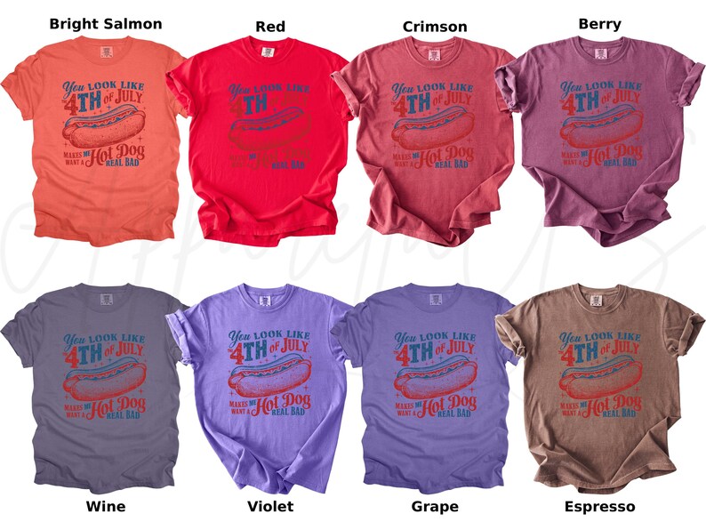 May include: Assorted-color t-shirts with a vintage design for the 4th of July. Each shirt features a hot dog graphic and the text "You look like 4th of July makes me a real bad hot dog". Colors include bright salmon, red, crimson, berry, wine, violet, grape, and espresso.