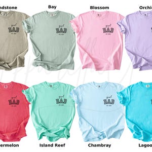 May include: Eight different colored t-shirts are displayed, each with the words "girl DAD est. 2023" printed on the front. The colors include sandstone, bay, blossom, orchid, watermelon, island reef, chambray, and lagoon.
