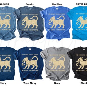 May include: A collection of eight t-shirts in various colors, including blue, navy, grey, and black. Each shirt features a beige cat graphic holding a snake, with the phrases "NO GODS NO MASTERS" and "NI DIEU NI MAITRE" printed above and below the graphic.