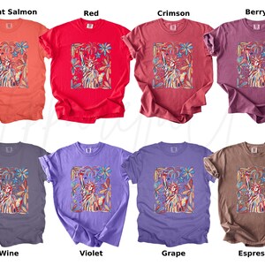 Puede incluir: Ocho camisetas de manga corta en varios colores: salm&oacute;n brillante, rojo, carmes&iacute;, baya, vino, violeta, uva y espresso. Cada camiseta presenta un gr&aacute;fico de la Estatua de la Libertad dentro de un marco floral.