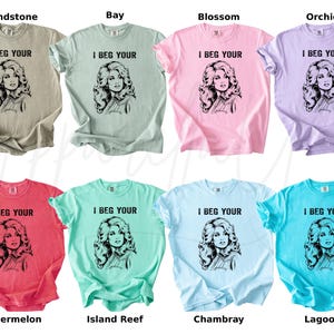 May include: Eight short-sleeved crew neck t-shirts in various colors including sandstone, bay, blossom, orchid, watermelon, island reef, chambray, and lagoon. Each shirt features a black graphic print of a woman and the text I BEG YOUR.