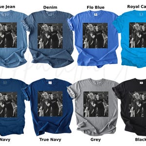 May include: A collection of eight t-shirts in various colors, including blue, navy, grey, and black. Each shirt features a black and white image of a group of people. The shirts are short-sleeved and have a crew neck.
