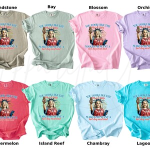 Puede incluir: Una colecci&oacute;n de camisetas en varios colores, incluyendo beige, verde, rosa, morado, rojo, verde azulado, azul claro y turquesa. Cada camiseta presenta un gr&aacute;fico de una mujer que se asemeja a la Estatua de la Libertad con el texto "You look like the 4th of July makes me want a hot dog real bad."