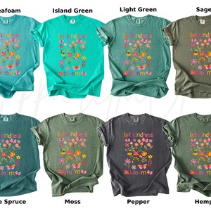 Pode incluir: Oito camisetas em v&aacute;rias cores, incluindo verde-&aacute;gua, verde-ilha e s&aacute;lvia. Cada camisa apresenta o texto "let kindness bloom" com um design floral e borboletas. Roupas casuais.