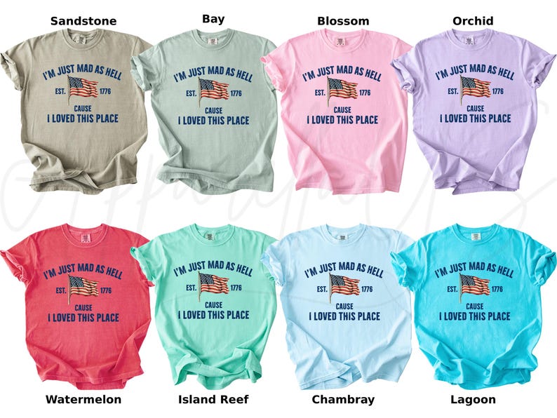 May include: A collection of eight short-sleeved t-shirts in various colors, each featuring the phrase "I'M JUST MAD AS HELL" above an American flag graphic and the text "CAUSE I LOVED THIS PLACE". Colors include sandstone, bay, blossom, orchid, watermelon, island reef, chambray, and lagoon.