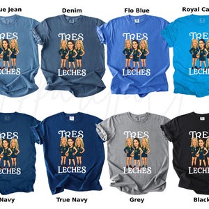 May include: A collection of t-shirts in various colors, including blue jean, denim, and black. Each shirt features a cartoon graphic of three women and the words "TRES LECHES" in white. The shirts are short-sleeved and have a crew neck.