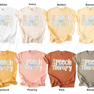 May include: A collection of t-shirts in various colors, including white, ivory, butter, banana, mustard, peachy, yam, and khaki. Each shirt features the text "Speech Therapy" in a decorative font with a bow graphic.