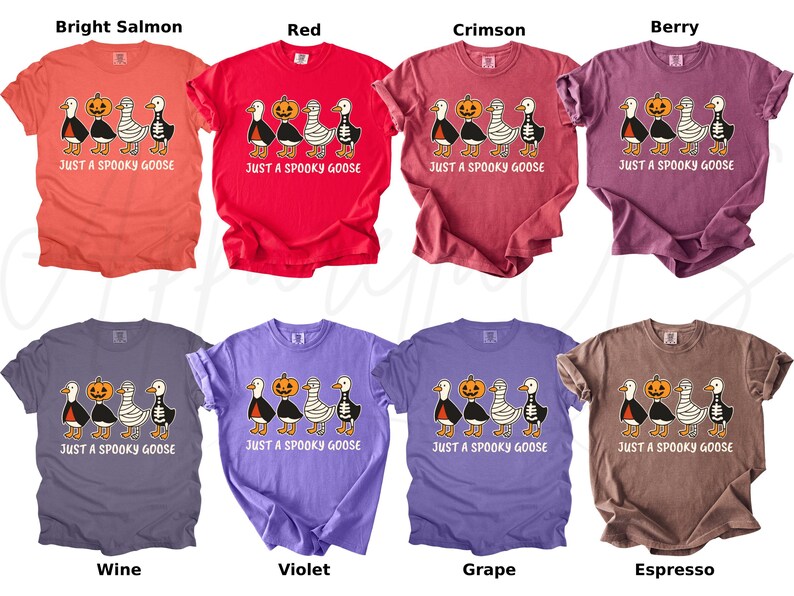 K&ouml;nnte beinhalten: Eine Kollektion von acht T-Shirts in verschiedenen Farben, jeweils mit einem Halloween-Motiv. Das Design zeigt Cartoon-G&auml;nse, einen K&uuml;rbis und den Text "JUST A SPOOKY GOOSE". Farben sind helles Lachs, Rot, Karmesinrot, Beere, Wein, Violett, Traube und Espresso.