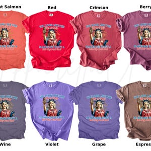 Puede incluir: Una colecci&oacute;n de ocho camisetas coloridas, cada una con un gr&aacute;fico de una mujer que se asemeja a la Estatua de la Libertad. Las camisetas vienen en varios colores, incluyendo salm&oacute;n brillante, rojo, carmes&iacute;, baya, vino, violeta, uva y espresso.