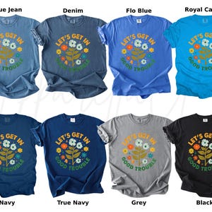 Peut inclure: Plusieurs t-shirts &agrave; manches courtes de couleurs vari&eacute;es, dont bleu, marine, gris et noir. Chaque t-shirt arbore l'inscription "LET'S GET IN GOOD TROUBLE" avec un motif floral. Une gamme de couleurs est propos&eacute;e.