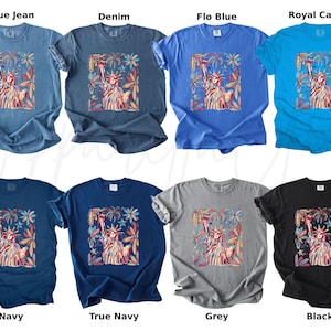Puede incluir: Ocho camisetas en varios colores, incluyendo azul vaquero, denim, flo blue, royal caribe, azul marino, azul marino verdadero, gris y negro. Cada camiseta presenta un gr&aacute;fico colorido de la Estatua de la Libertad rodeada de elementos florales.