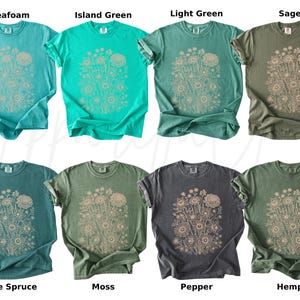 Pode incluir: Oito camisetas em v&aacute;rias cores, incluindo verde-&aacute;gua, verde-ilha, verde-claro e s&aacute;lvia. Cada camiseta apresenta um design floral em um tom neutro. As cores incluem abeto azul, musgo, pimenta e c&acirc;nhamo.