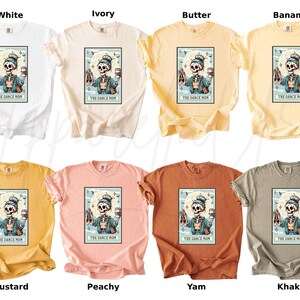May include: A collection of eight t-shirts in various colors, including white, ivory, butter, banana, mustard, peachy, yam, and khaki. Each shirt features a graphic of a skeleton holding ballet shoes and a coffee cup, with the text "The Dance Mom".