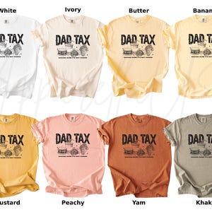 May include: A collection of eight t-shirts in various colors, including white, ivory, butter, banana, mustard, peachy, yam, and khaki. Each shirt features the text "DAD TAX" above a graphic of food items.
