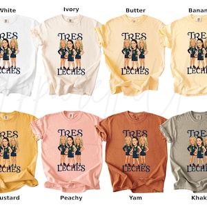 May include: A collection of t-shirts in various colors, including white, ivory, butter, banana, mustard, peachy, yam, and khaki. Each shirt features a graphic of three women and the text "TRES LECHES" in a dark blue color.