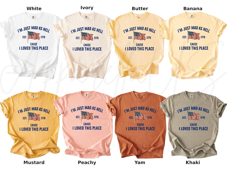 May include: A collection of short-sleeved t-shirts in various colors, including white, ivory, and mustard. Each shirt features the text "I'M JUST MAD AS HELL CAUSE I LOVED THIS PLACE" with an American flag graphic.