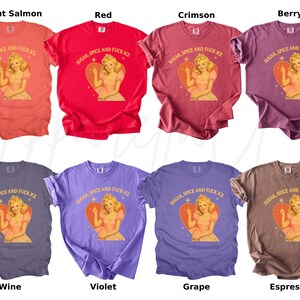 Peut inclure: Huit t-shirts de couleurs vari&eacute;es, dont saumon clair, rouge, cramoisi, baie, vin, violet, raisin et expresso. Chaque t-shirt pr&eacute;sente un motif d'une femme dans un c&oelig;ur avec le texte "SUGAR, SPICE AND FUCK ICE".