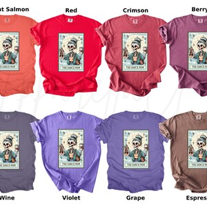 May include: A collection of eight t-shirts in various colors, including bright salmon, red, crimson, berry, wine, violet, grape, and espresso. Each shirt features a graphic of a skeleton with ballet shoes and a coffee cup, with the text "THE DANCE MOM".