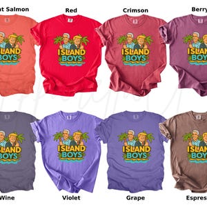 Pu&ograve; includere: Una collezione di otto t-shirt in vari colori, tra cui salmone brillante, rosso, cremisi, bacca, vino, viola, uva e espresso. Ogni maglietta presenta il testo "ISLAND BOYS" e un'illustrazione di due uomini e palme.