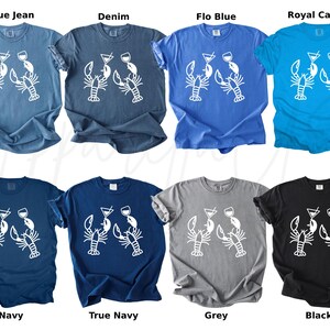 K&ouml;nnte beinhalten: Acht T-Shirts in verschiedenen Farben, darunter Blau, Grau und Schwarz. Jedes Shirt hat eine wei&szlig;e Grafik von zwei Hummern mit Cocktailgl&auml;sern. Die Shirts sind kurz&auml;rmlig und aus einem weichen Material gefertigt.