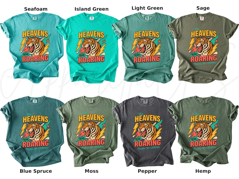 May include: A collection of eight t-shirts in various colors, including seafoam, island green, and sage. Each shirt features a graphic of a roaring tiger with the text "HEAVENS are ROARING".