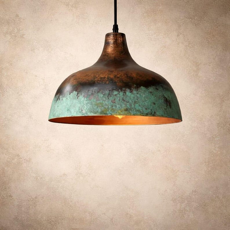 May include: A hanging pendant light with a copper-colored top and a turquoise-green bottom. The interior of the light fixture is a warm orange-gold color. The light hangs from a black cord.