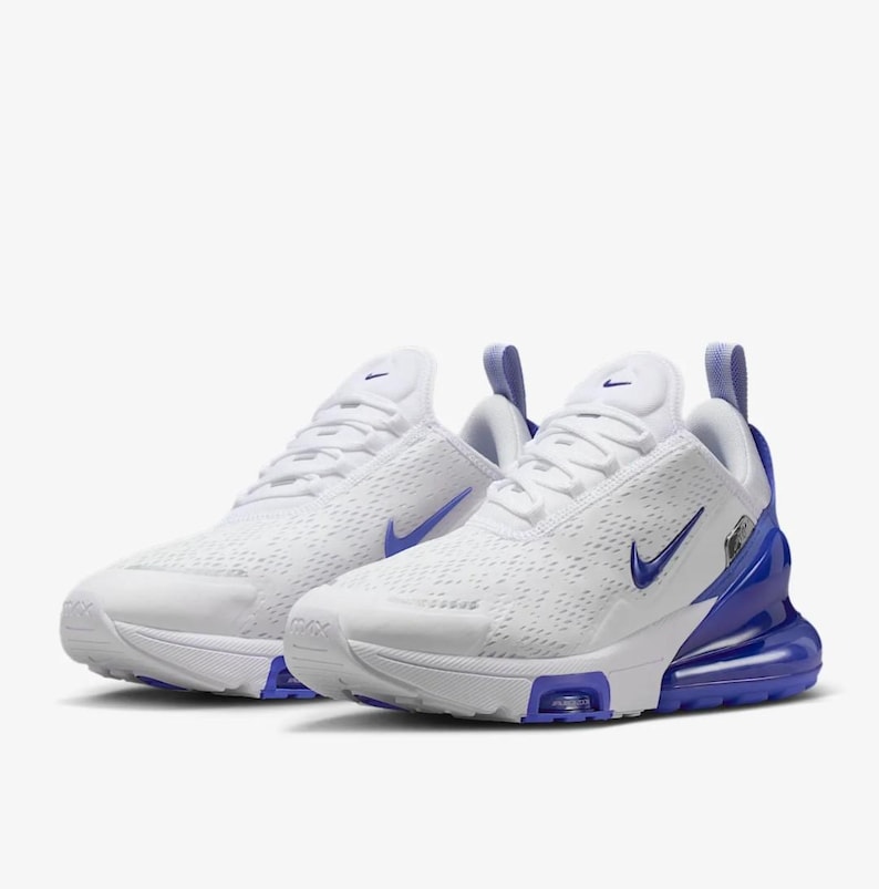 Op de afbeelding: Paar witte sportschoenen met blauwe accenten. De schoenen hebben een ademend mesh bovenwerk, een blauw swoosh-logo en een zichtbare air unit in de hiel. Het ontwerp omvat een treklipje aan de hiel en een witte zool.