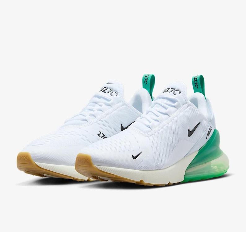 May include: Pair of white athletic shoes with green and tan accents. The shoes feature a mesh upper, black swoosh logos, and the number "270" printed on the side. The soles are tan and the air bubble is green.