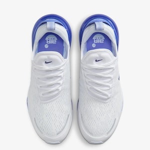 Op de afbeelding: Bovenaanzicht van witte sportschoenen met blauwe accenten. De schoenen hebben een mesh bovenwerk, witte veters en een blauwe hielkap. Het Nike-logo is zichtbaar. De zool is wit met een blauwe luchtbel.