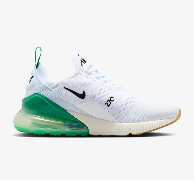 May include: White and green athletic shoe with a black Nike swoosh. The shoe features a white mesh upper, a green heel counter, and a visible air unit. The sole is a combination of white, green, and tan.