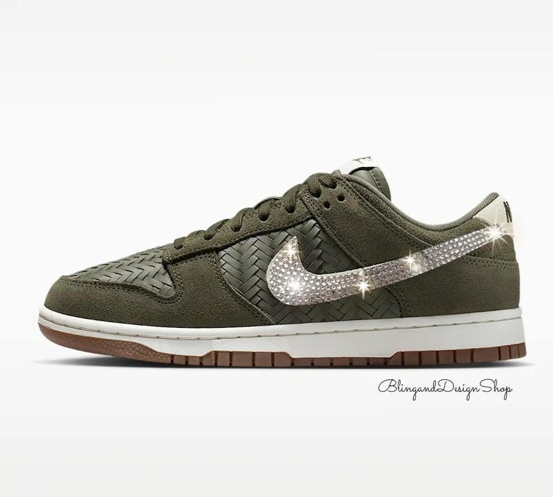 Puede incluir: Zapatillas Nike Dunk Low verde oliva con entresuela blanca y suela marr&oacute;n. El logo de Nike est&aacute; adornado con brillantes pedrer&iacute;a. El zapato presenta una textura tejida en los laterales y la puntera.