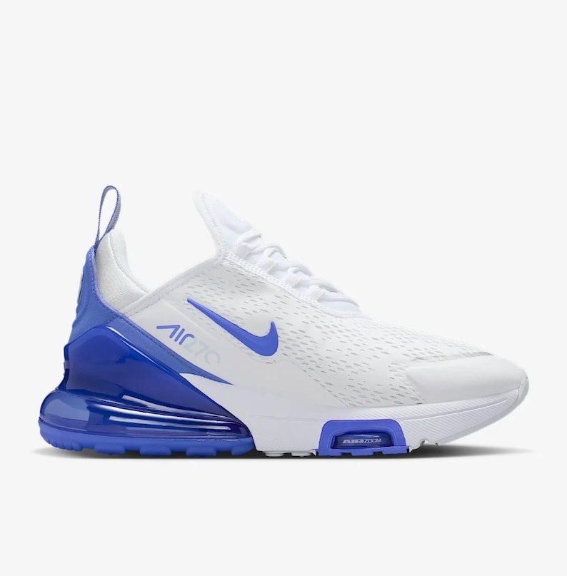 Op de afbeelding: Witte en blauwe sportschoen met de tekst "AIR 270" en een Nike swoosh. De schoen heeft een wit mesh bovenwerk, blauwe accenten op de hiel en zool en een zichtbare air unit.