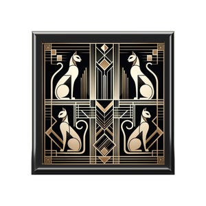 May include: Square black framed art print featuring four stylized cats in a symmetrical Art Deco design. The cats are cream-colored, set against a black background with gold geometric patterns.