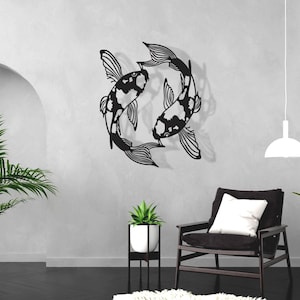Puede incluir: Arte de pared de metal negro con dos peces koi estilizados con marcas blancas, sobre una pared blanca con suelo negro. El arte se muestra en un salón con un sillón negro, una planta en maceta y una lámpara colgante blanca.