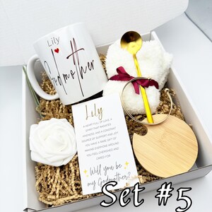 May include: A gift box with a white mug that says "Lily Godmother", a gold spoon, a white washcloth, a gold bracelet, a wooden coaster, a white rose, and a card that says "Will you be my Godmother?" Set #5.