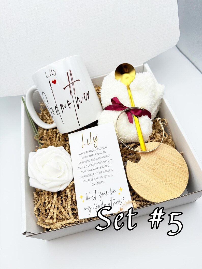 May include: A gift box with a white mug that says "Lily Godmother", a gold spoon, a white washcloth, a gold bracelet, a wooden coaster, a white rose, and a card that says "Will you be my Godmother?" Set #5.