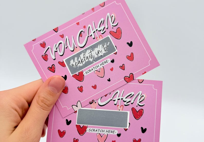 May include: Two pink scratch-off cards with a heart pattern. The top card says "You Can" with a silver scratch-off area that says "Breakfast in Bed". The bottom card says "Cher" with a silver scratch-off area.