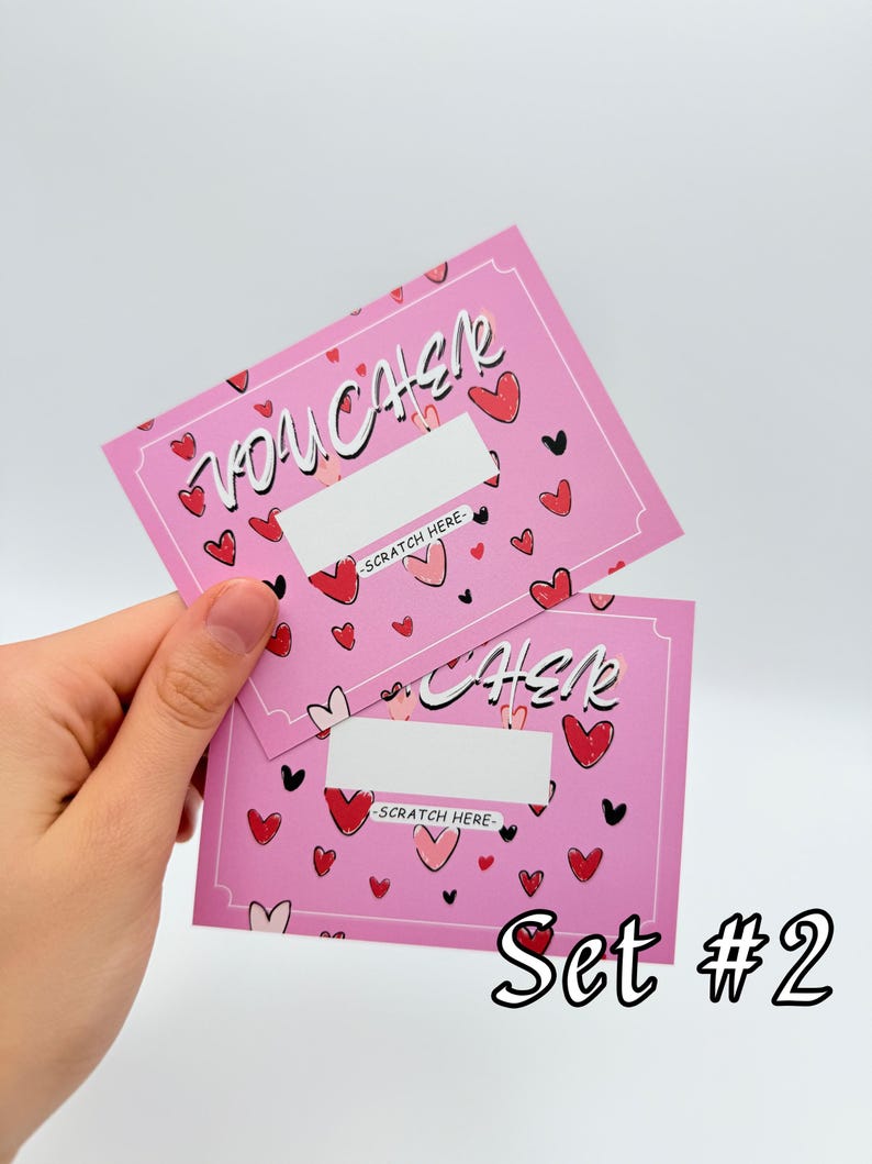 May include: Two pink scratch-off cards with a heart pattern and the text "Voucher" and "Check" with the words "Scratch Here" below each. The cards are labeled "Set #2".