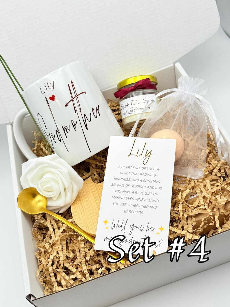 May include: A gift set in a white box, featuring a white mug with "Lily Godmother" in script, a small candle, a bath bomb, a gold spoon, a wooden coaster, and a card that says "Will you be my Godmother?" Set #4.
