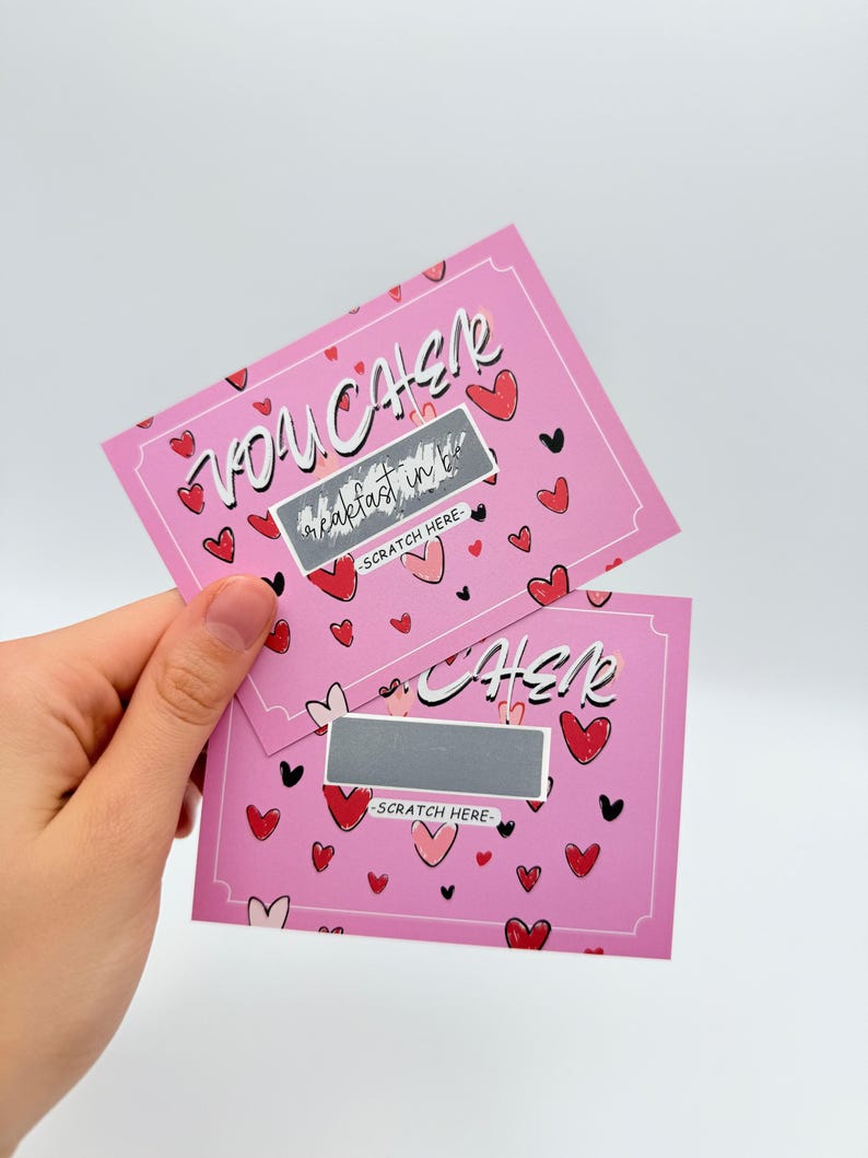May include: Two pink scratch-off cards with a heart pattern. The top card says "You  Catcher" and the bottom card says "Cher" with a silver scratch-off area. Both cards say "Scratch Here".
