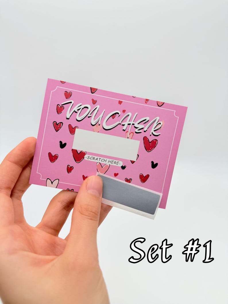 May include: Pink scratch-off voucher with a heart pattern and the word "VOUCHER" in white lettering. The voucher has a silver scratch-off area with the text "SCRATCH HERE" in black. Set #1 is written in black below the voucher.