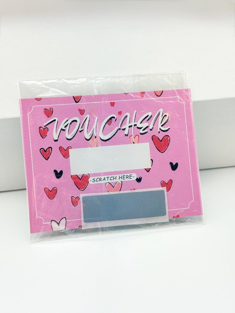 May include: Pink scratch-off voucher with a heart pattern and the word "VOUCHER" in white lettering. The voucher has a silver scratch-off area with the text "SCRATCH HERE" above it.