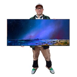 May include: A rectangular landscape painting showing a night sky with stars and a colorful aurora borealis over a shoreline. The artwork features shades of blue, purple, and yellow. The painting is held by a person.