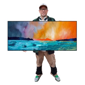 May include: An abstract landscape painting with a vibrant colour palette. The artwork features a turquoise sea, dark mountains, and a fiery orange and yellow sky. The painting is rectangular and framed in black.