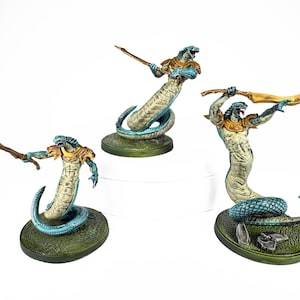 May include: Three painted miniature figurines depicting snake-like creatures with human torsos. Each figure features blue scales, tan skin, gold-coloured armour on the shoulders and chest, and holds a curved gold blade while standing on a green base.